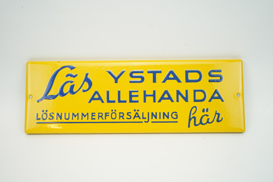 Skylt, "Läs Ystads Allehanda", emaljerad.
